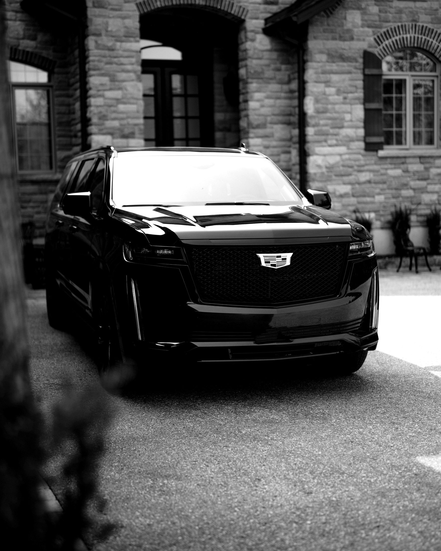 Matte black Cadillac Escalade parked in the courtyard of a private stone residence